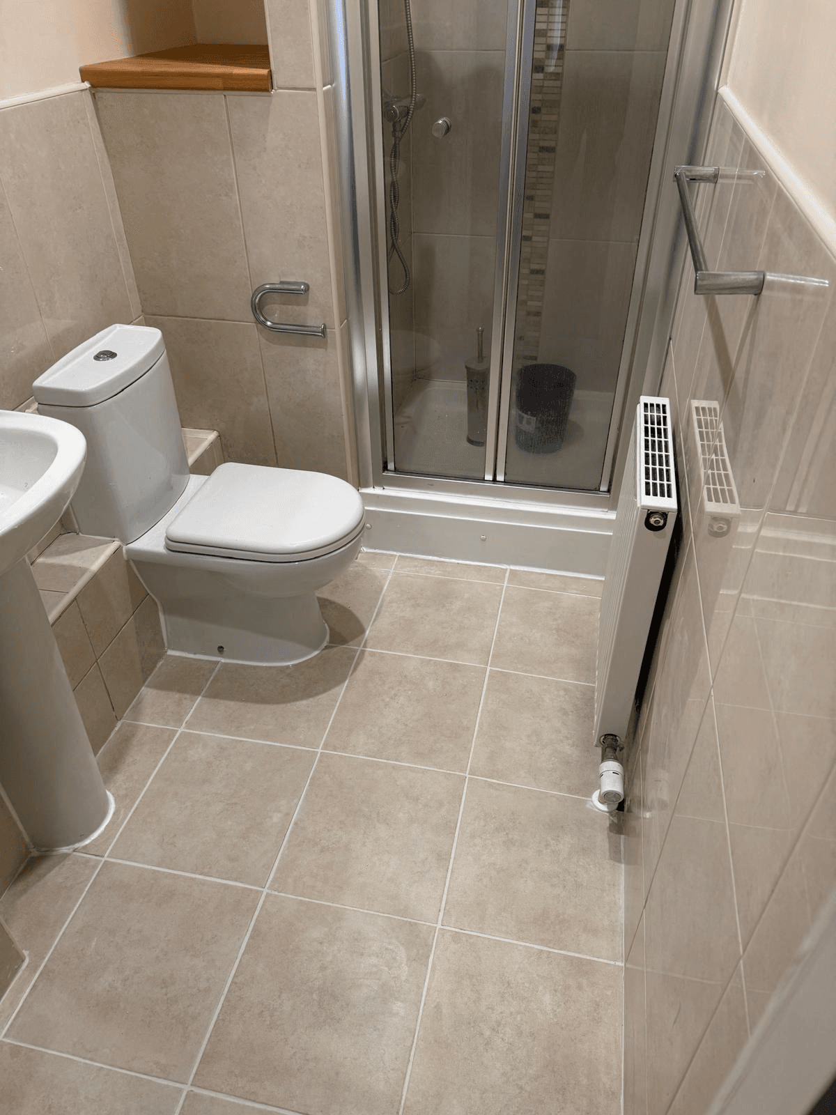 Complete bathroom suite with walk-in shower, WC and sink — fully tiled
