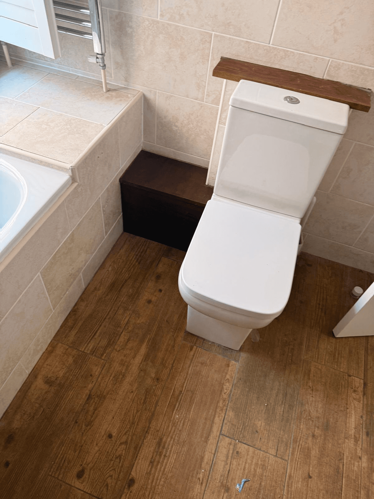 Finished bathroom with tiled walls, toilet and wood-effect flooring