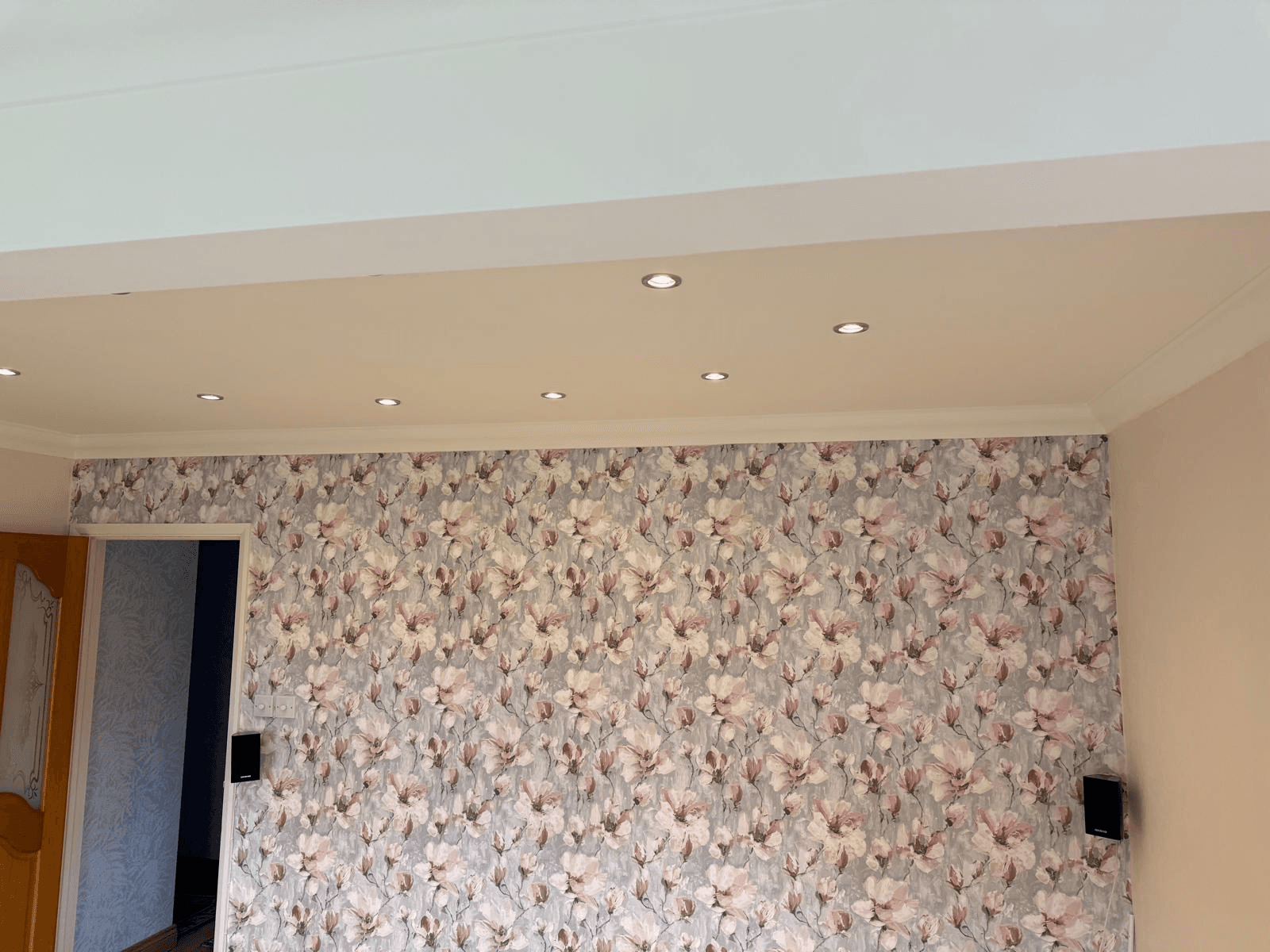 Smooth plastered ceiling with recessed spotlights and feature wallpaper wall
